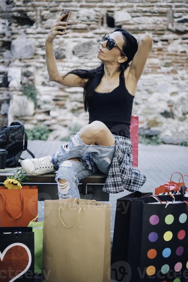 linda chica tomando selfie con bolsas de compras foto