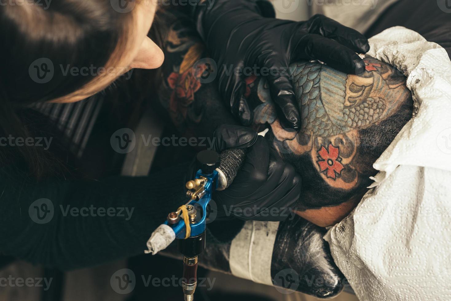 máquina de tatuaje de cerca. mujer creando una imagen a mano con ella en el salón foto