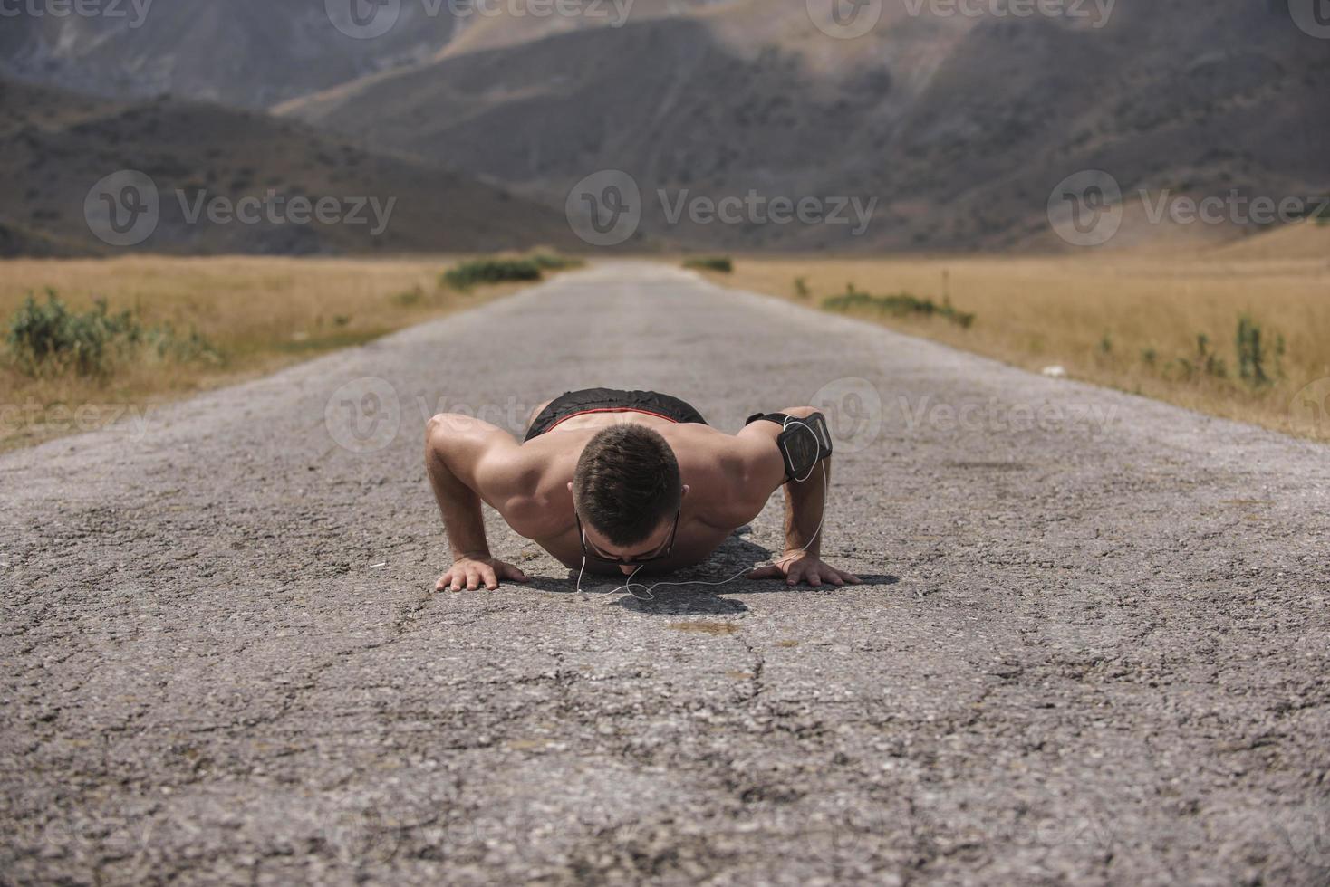 Male athlete exercising push up outside in sunny sunshine. Fit shirtless male fitness model in crossfit exercise outdoors. Healthy lifestyle concept. photo