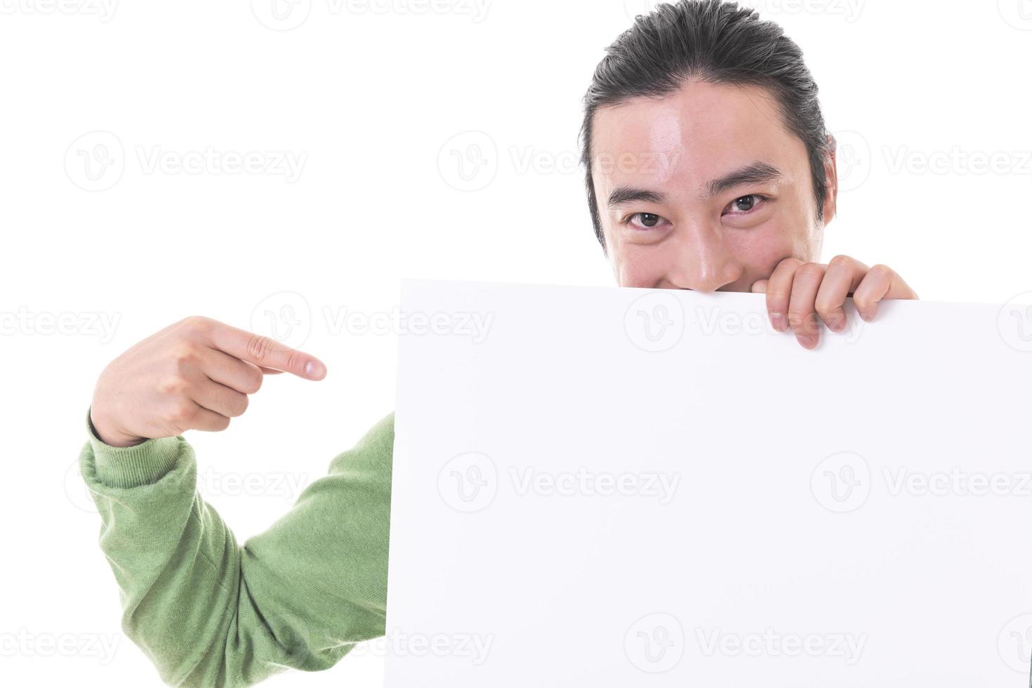 Portrait of young Asian man peeping at the camera holding white blank sign photo