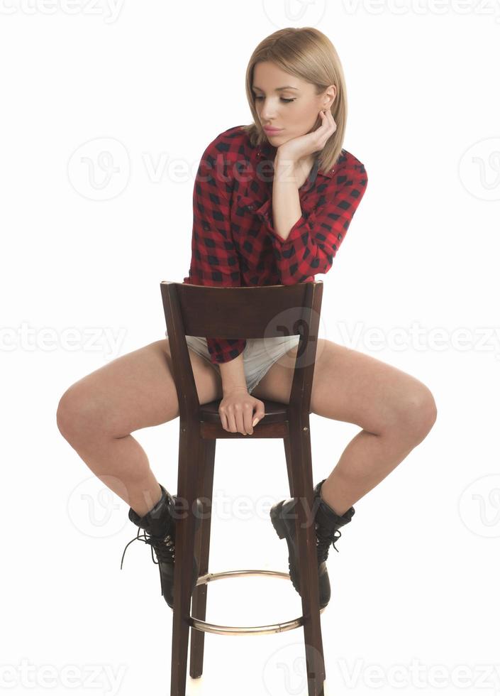 Smiling young woman sitting on stool. Isolated studio portrait on white back. photo