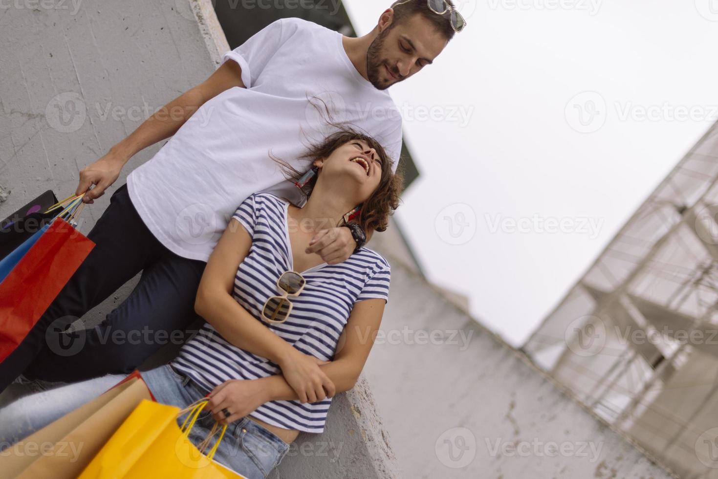 Portrait of cheerful Caucasian young couple man and woman holding many paper bags after shopping while walking and talking on street. Happy family couple with packages outdoor. Buying concept photo