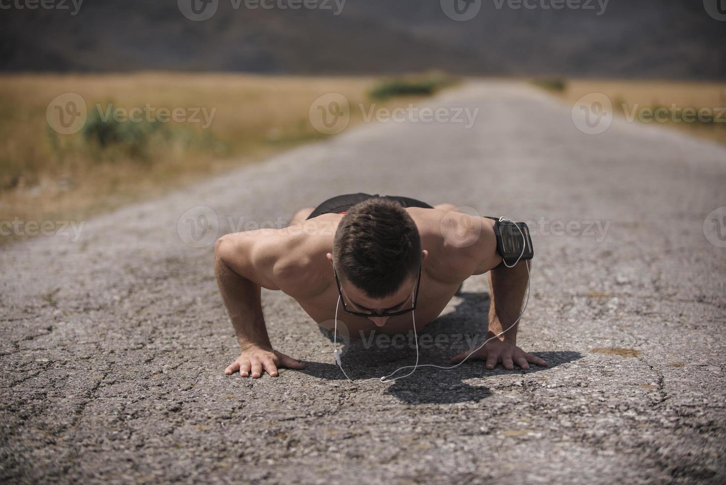 Male athlete exercising push up outside in sunny sunshine. Fit shirtless male fitness model in crossfit exercise outdoors. Healthy lifestyle concept. photo