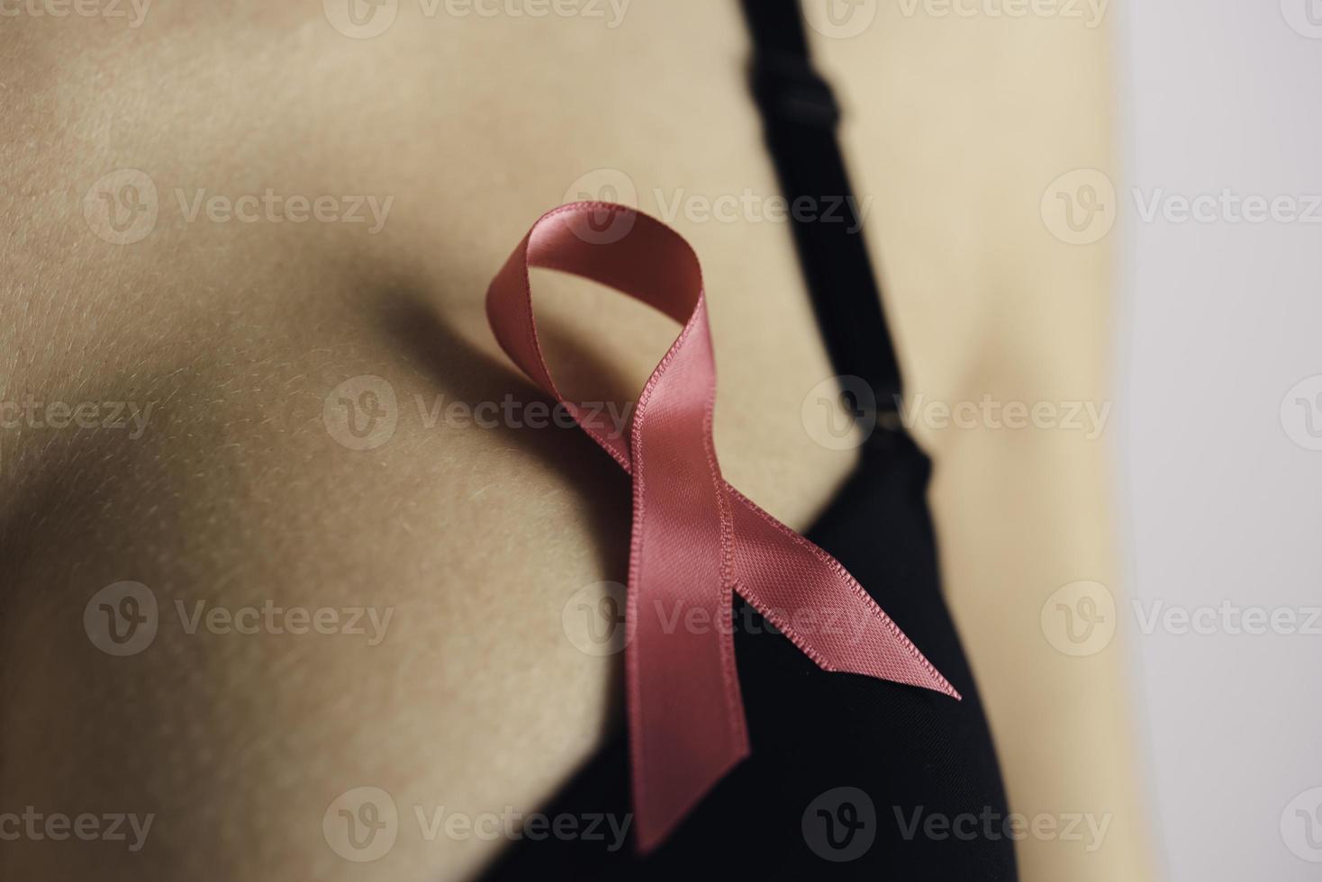 concepto de concienciación sobre el cuidado de la salud, la medicina y el cáncer de mama. mujer joven en sujetador con símbolo de cinta rosa foto