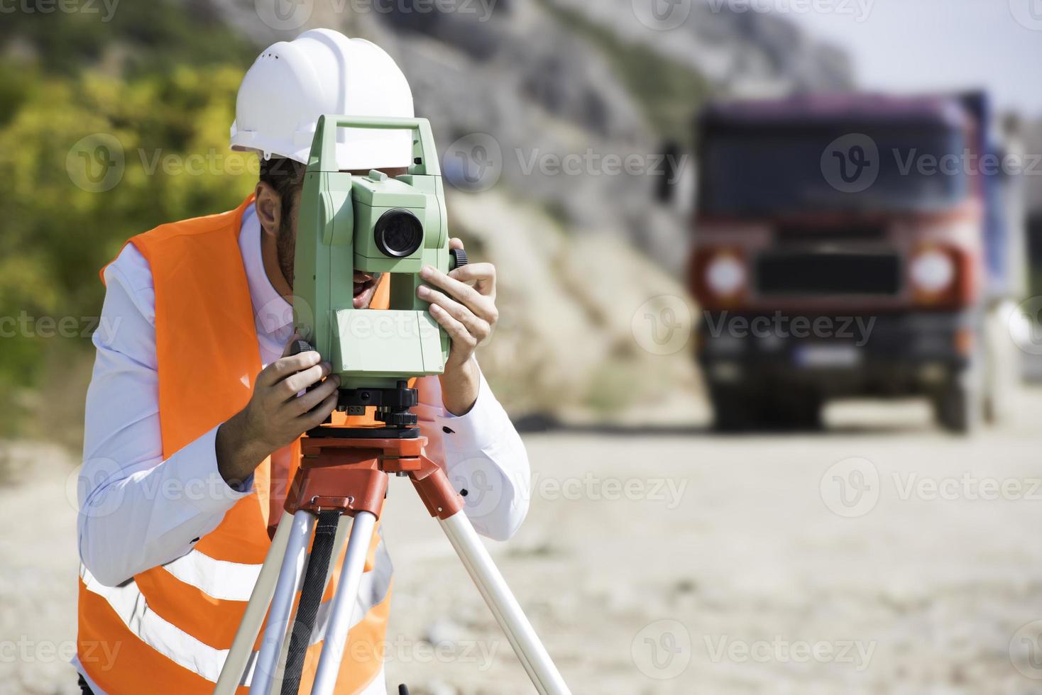 el ingeniero topógrafo está midiendo el nivel en el sitio de construcción. los topógrafos aseguran mediciones precisas antes de emprender grandes proyectos de construcción. foto