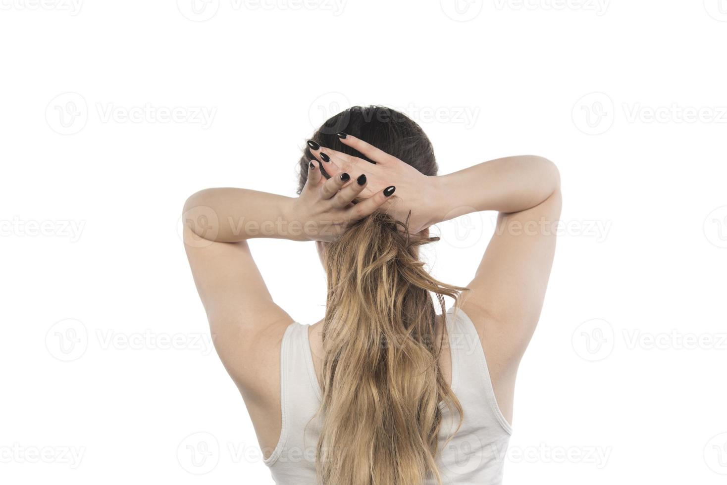 Female model arranging her hair. Woman tying hair in a bun. photo