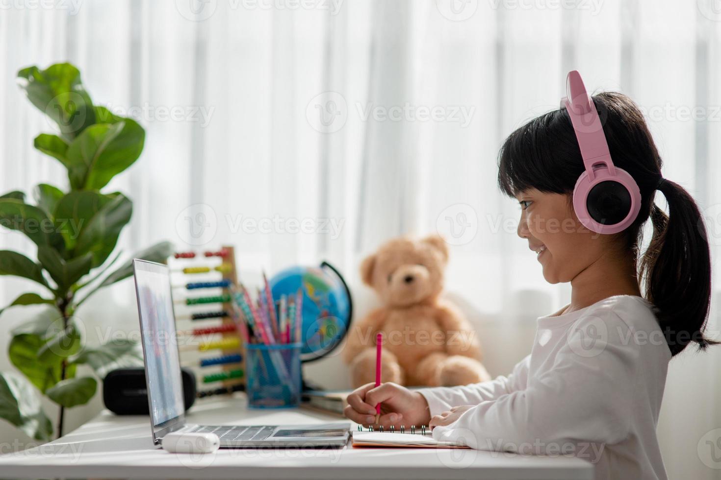 Asian little girl in headphones have video call distant class with teacher using laptop, study online on computer, homeschooling concept photo