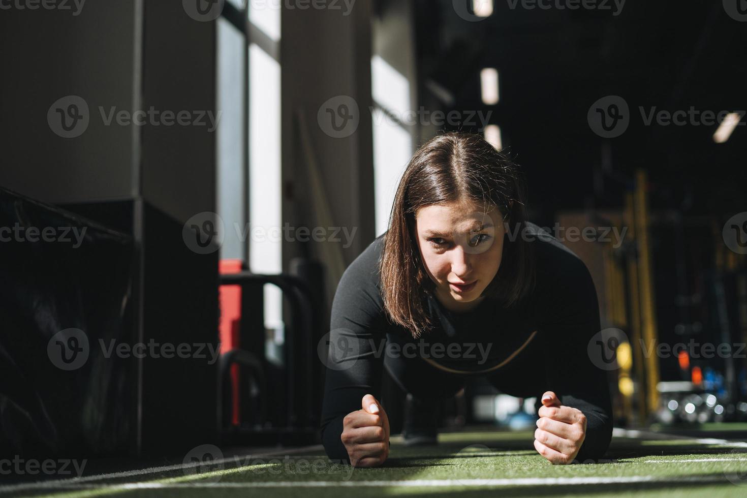 Young brunette woman training her muscles in the fitness club gym photo