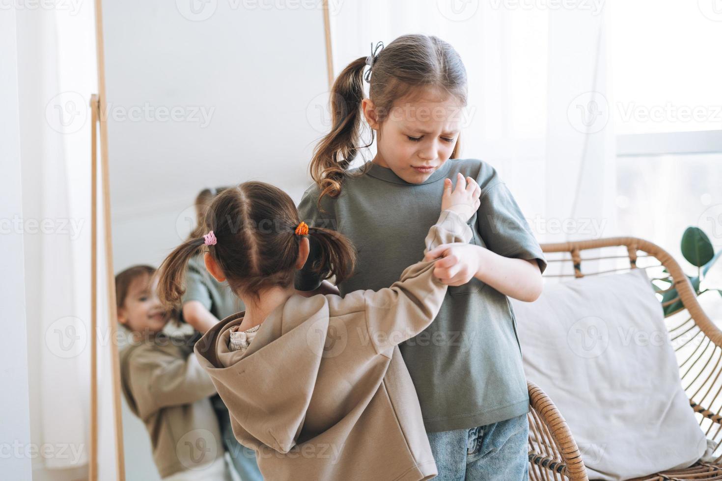 Little girls sisters have fight near mirror in children room at the home photo