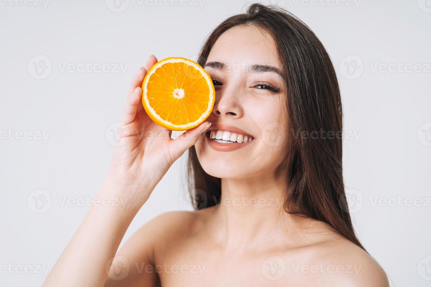 retrato divertido de belleza de mujer asiática sonriente feliz con cabello largo oscuro con naranjas en las manos sobre fondo blanco aislado foto