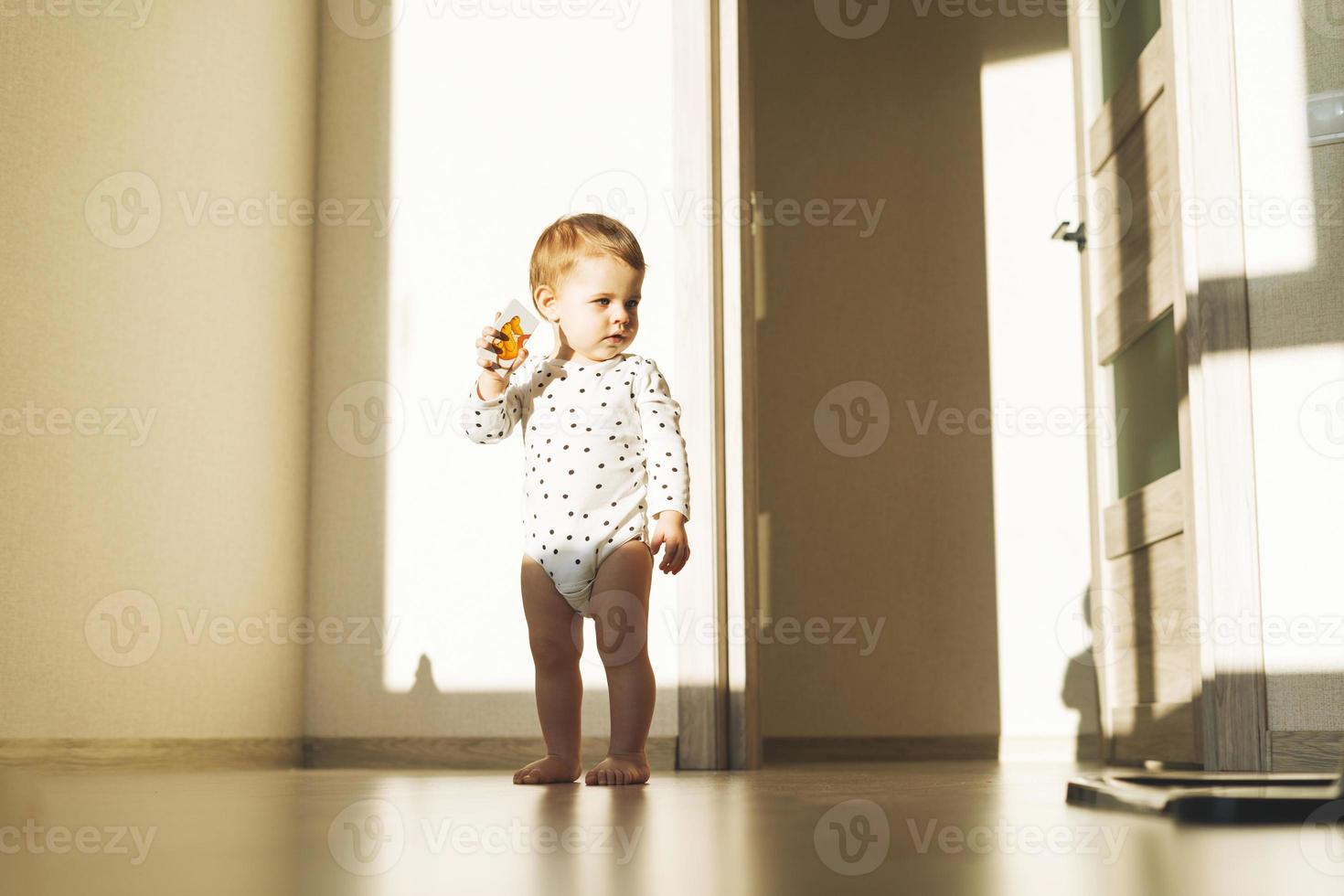 Cute baby girl in emty children room with hard light at home photo