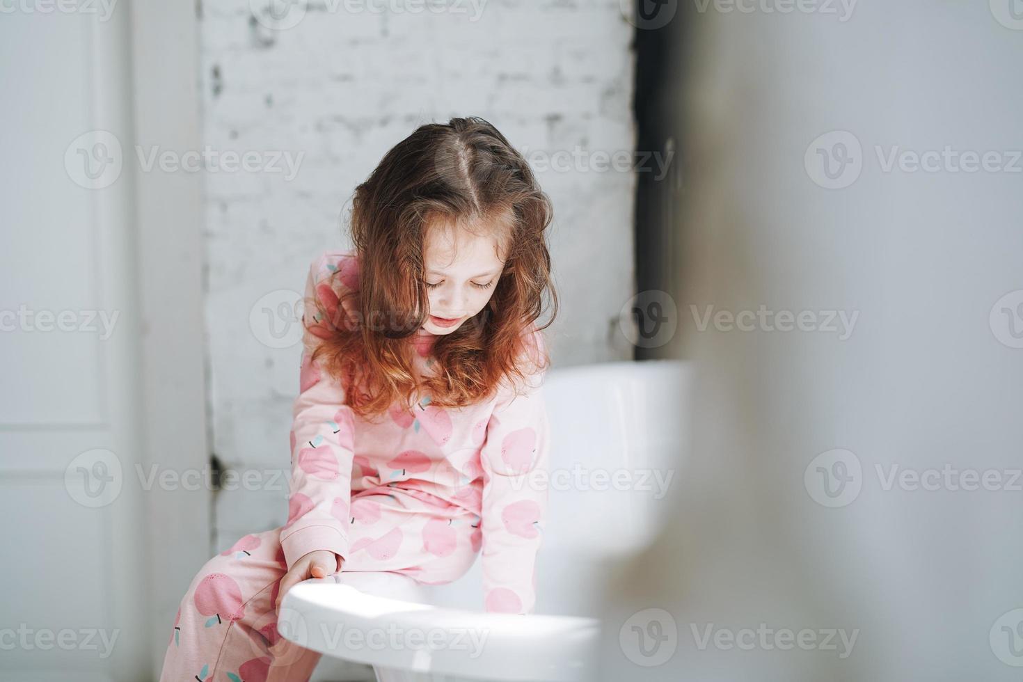 Happy little girl in pajamas having fun in bath with foam at home photo