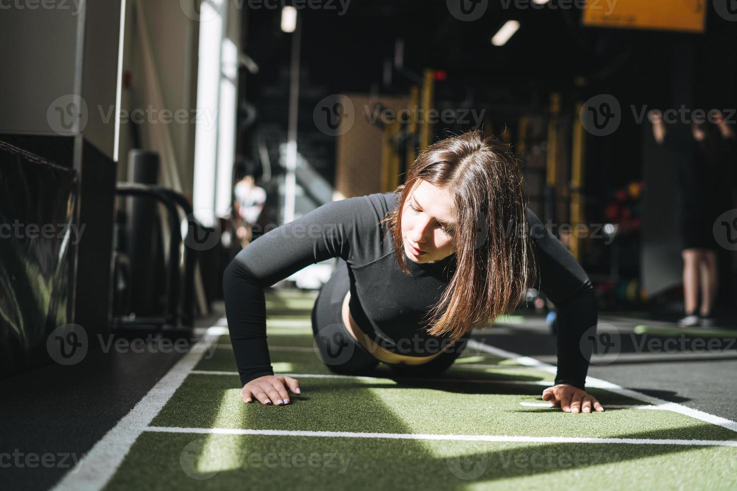 Young brunette woman training her muscles in the fitness club gym photo
