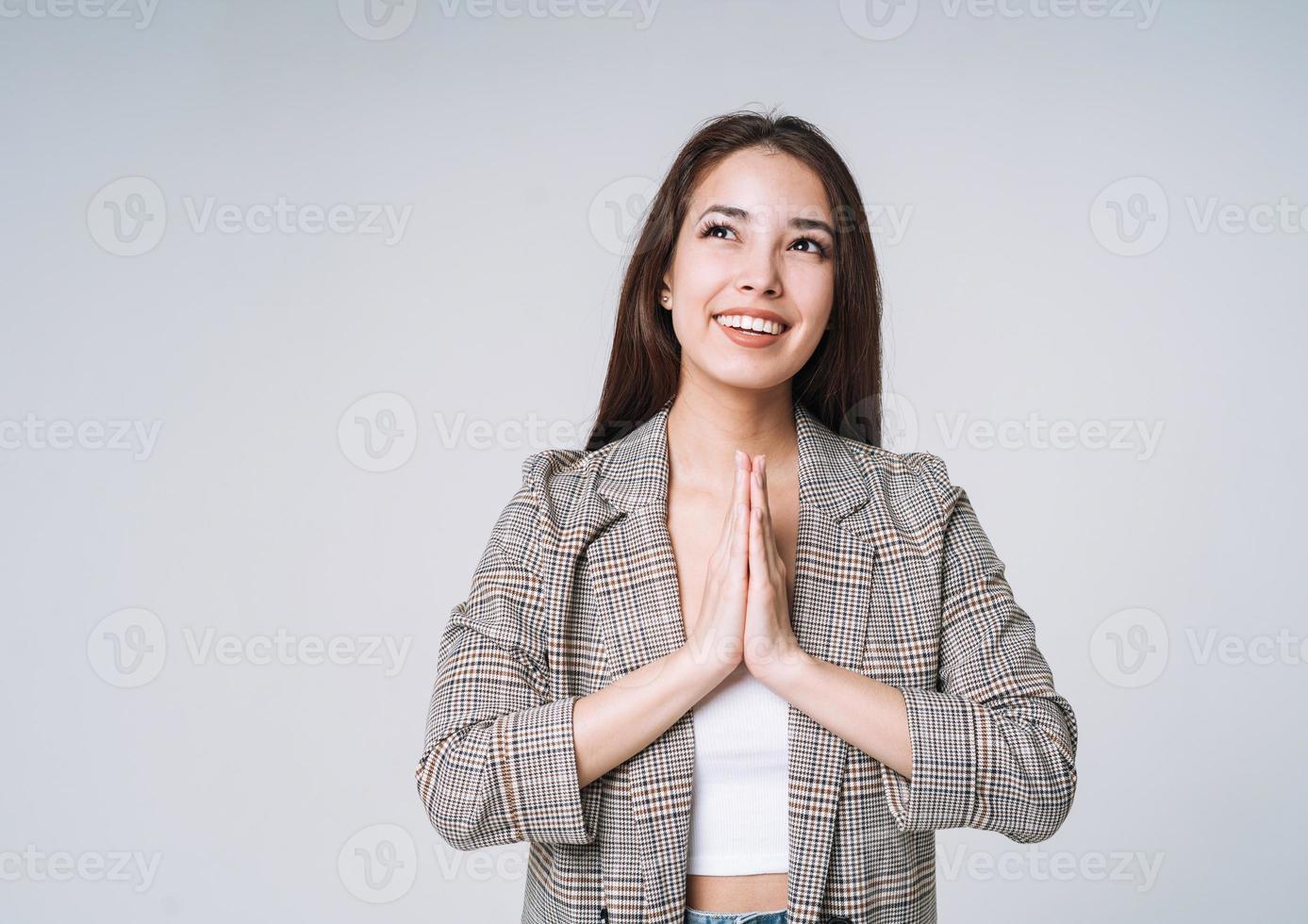 joven mujer asiática feliz con el pelo largo en traje sobre fondo gris foto