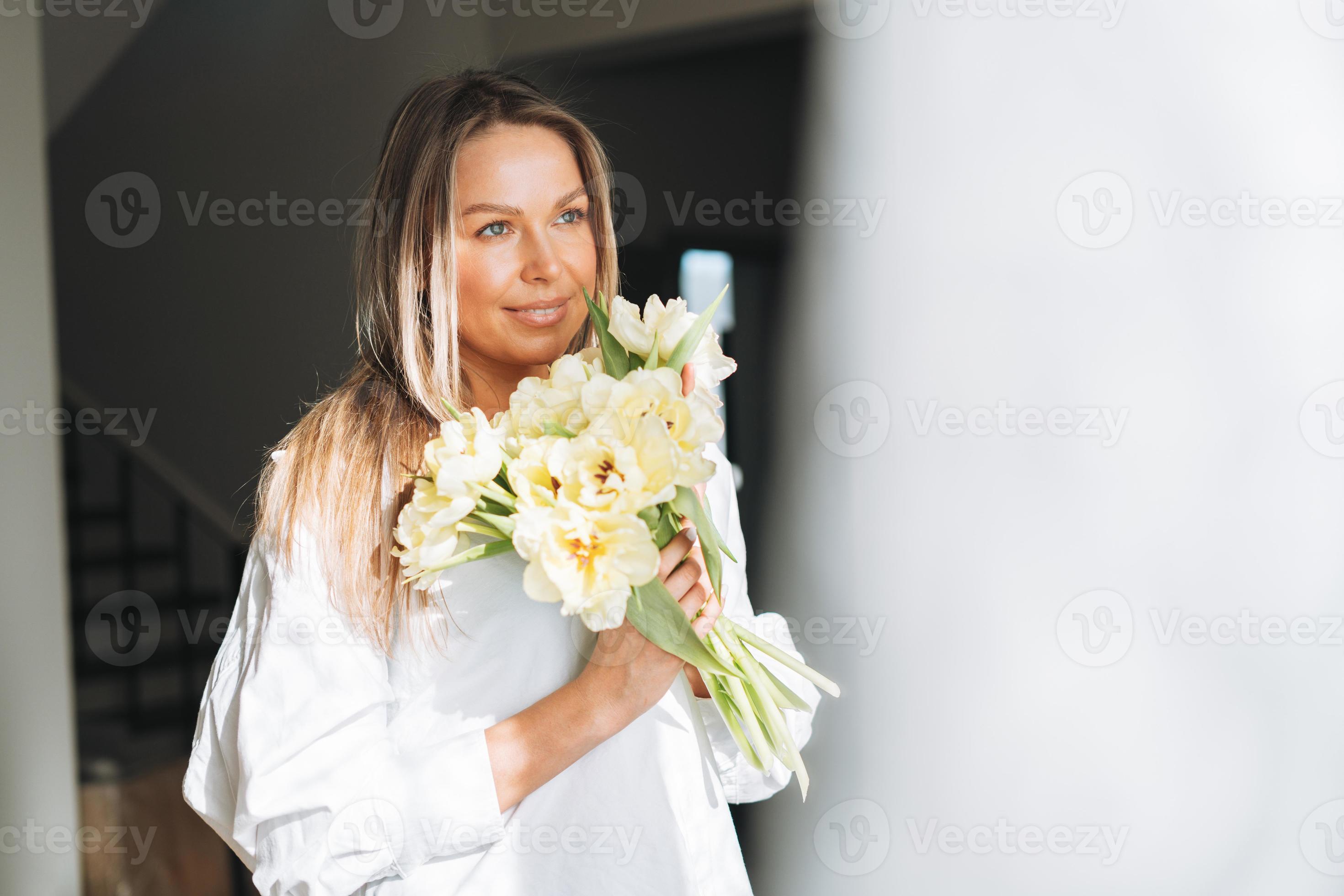 Hermosa novia. hermosa mujer con cabello largo con una túnica blanca en la  ventana.