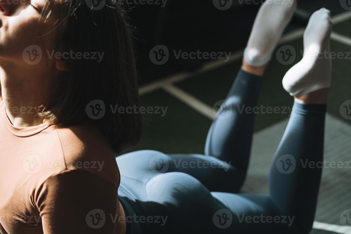 joven morena haciendo pilates de estiramiento, practica yoga en la alfombra en el gimnasio foto