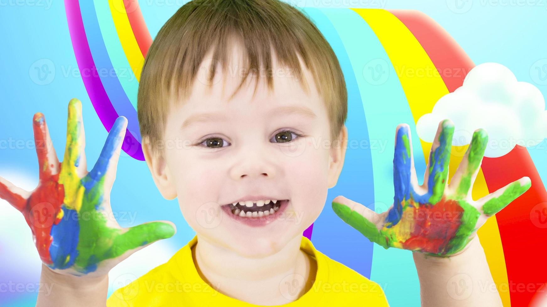 A boy with a smile on his face and his hands painted with watercolor paint. Kindergarten. photo