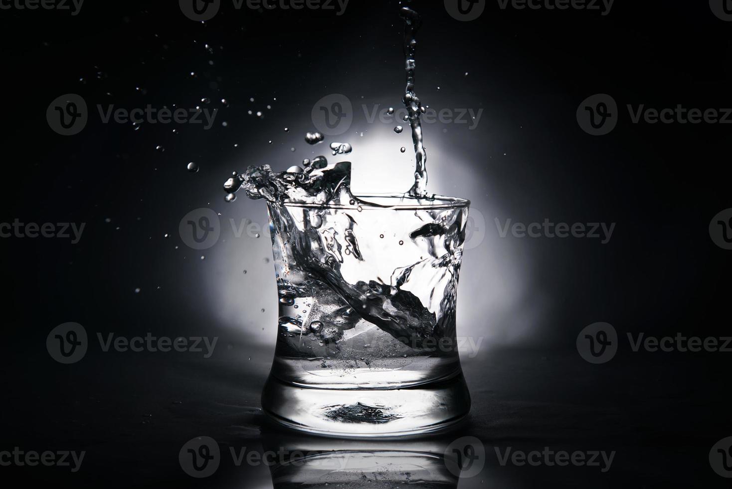 ice cube splashing into a glass full of water photo