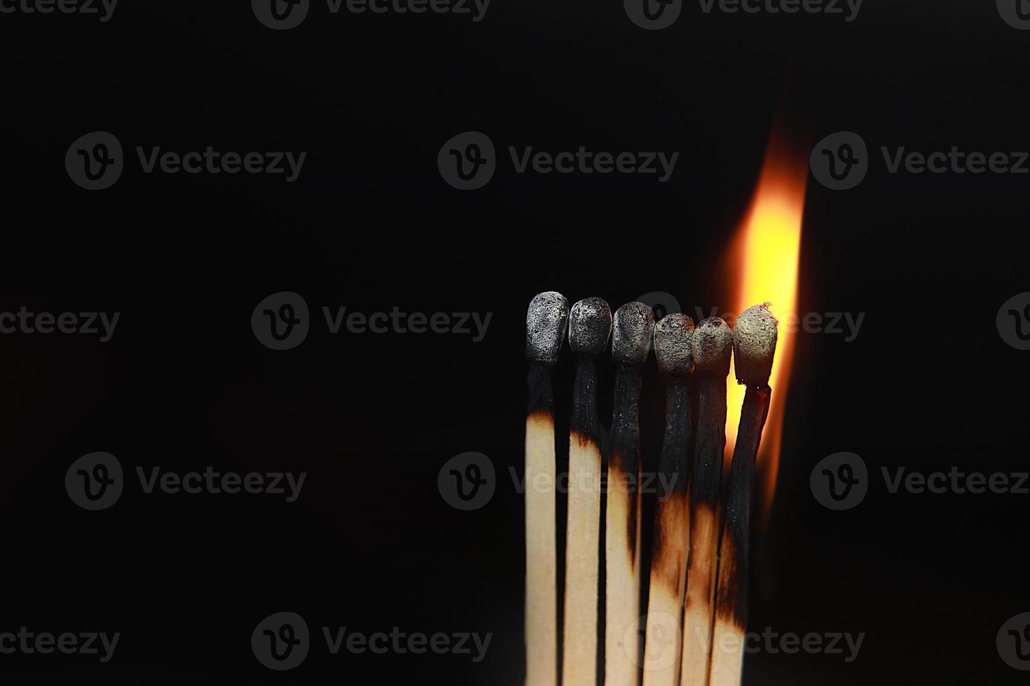 fósforos encendidos sobre fondo negro. las cerillas en llamas en la fila de la quema son una secuencia mientras una cerilla permanece apagada para evitar que el fuego se conecte contra el fondo negro foto