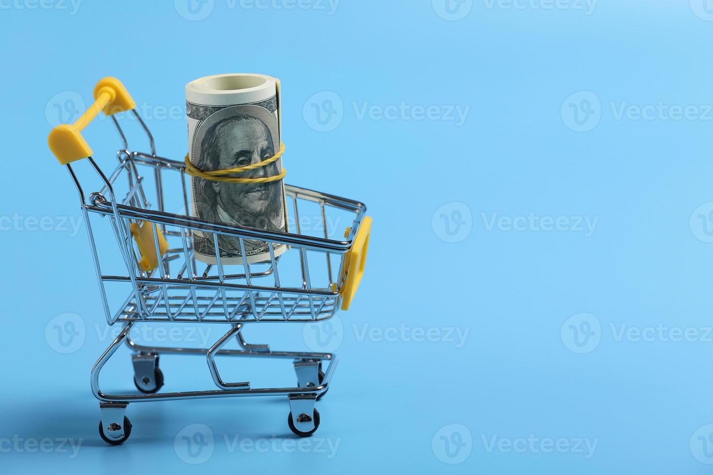 shopping time. dollars roll in shopping cart on blue background. time is money. Time management concept. money in the basket. selective focus. place for text photo