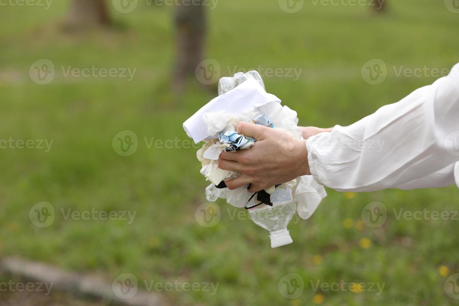 woman throws plastic garbage in the trash. woman hand picking up garbage plastic for cleaning at park. garbage collection after a pandemic. selective focus photo