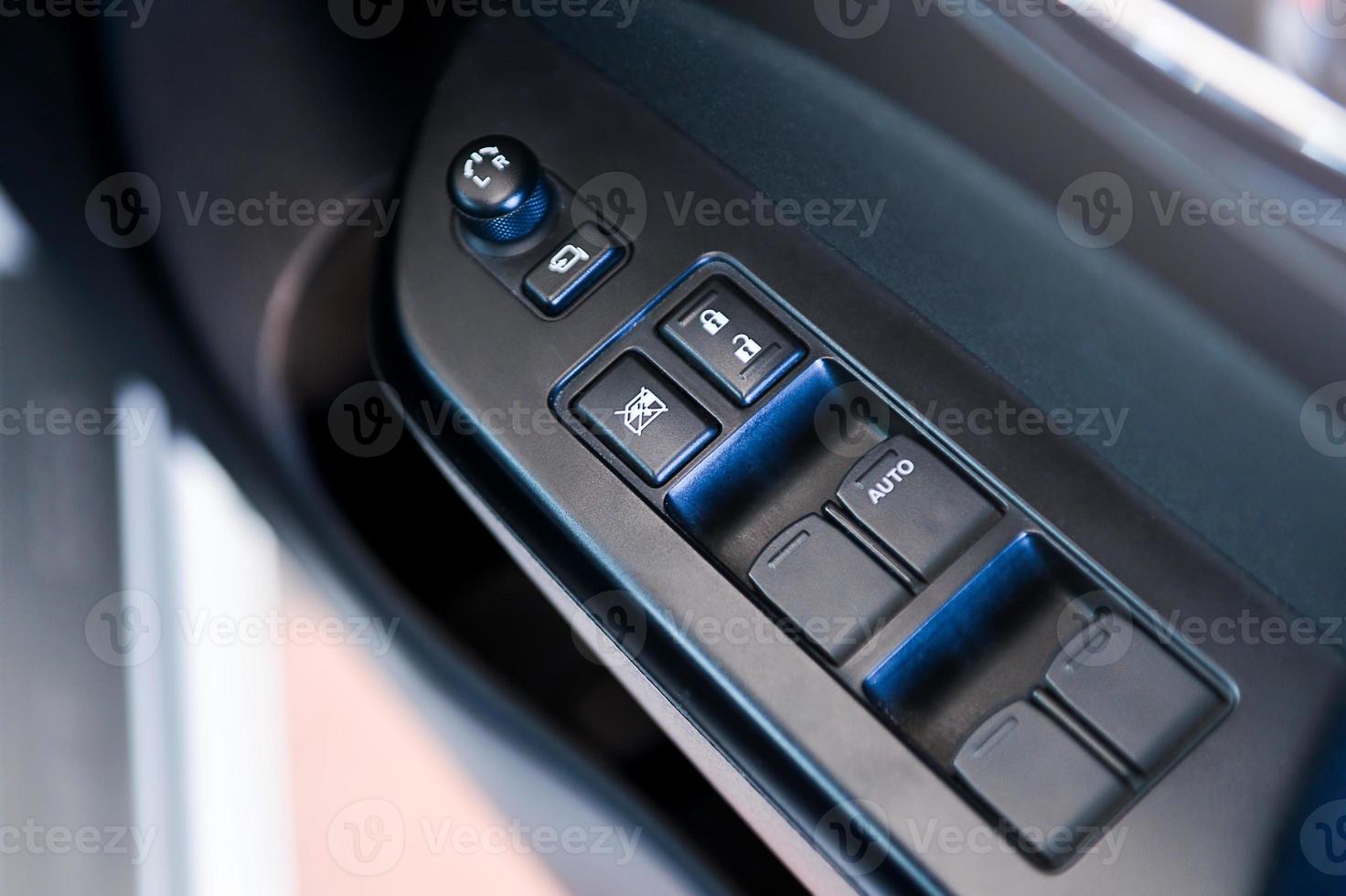 Car door interior arm rest with window control panel, door lock button, and mirror control. photo