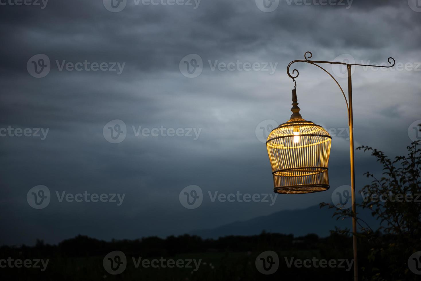 White bird cage as Lamp against dark sky photo