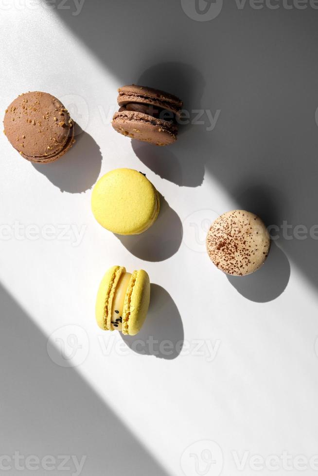 Sweet yellow lemon and brown chocolate french macaroons or macarons dessert isolated on white background with light rays from window photo