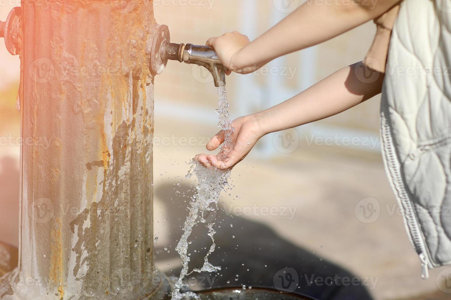child hands under drinking fresh water tap on the beach on a bright Sunny day by the sea. High quality photo