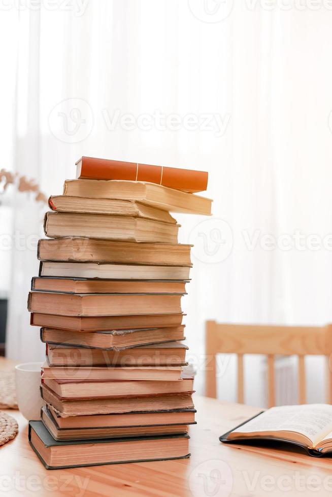 Stack books or textbooks and one opened book on wooden desk in room. Literature research. Concept - information search in books. Back to school. Education and school concept. copy space. photo