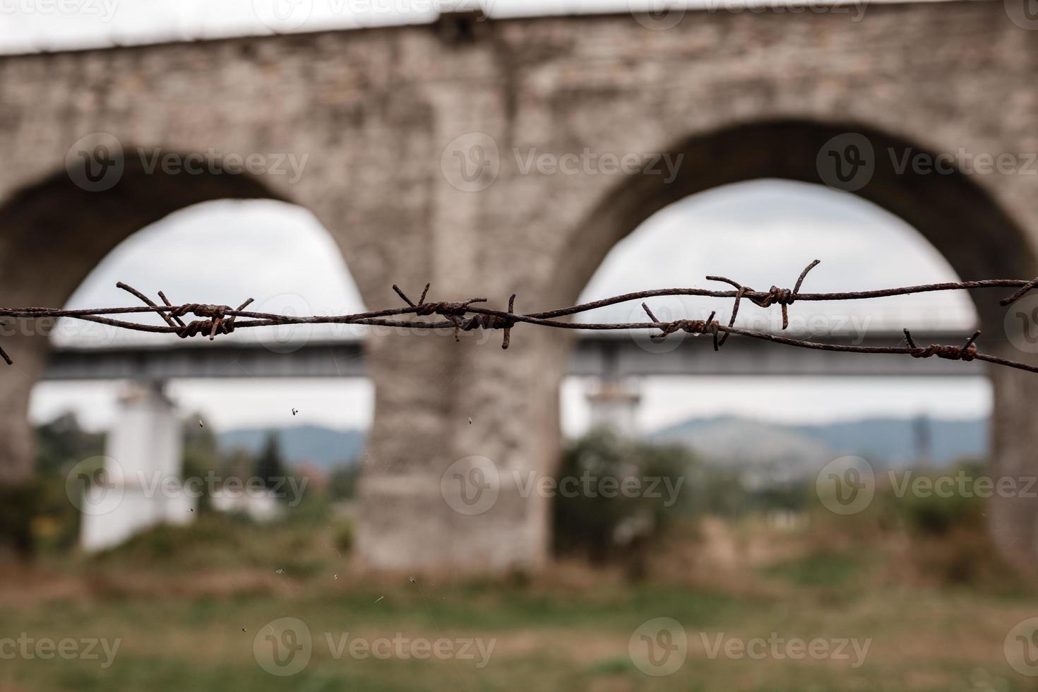 barbed fence in the foreground. on the background of a viaduct. photo