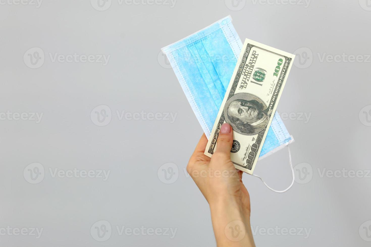 Hand holding medicine protective mask with banknote of dollar on white background. Coronavirus covid 19 quarantine concept. photo