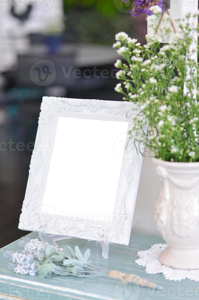 Blank  frame on the table and flower vase photo