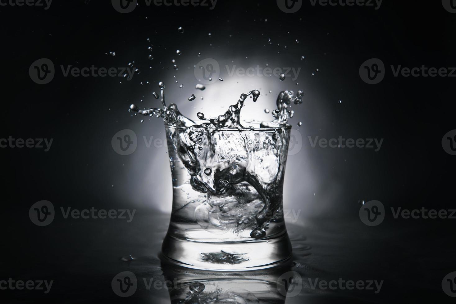 ice cube splashing into a glass full of water photo