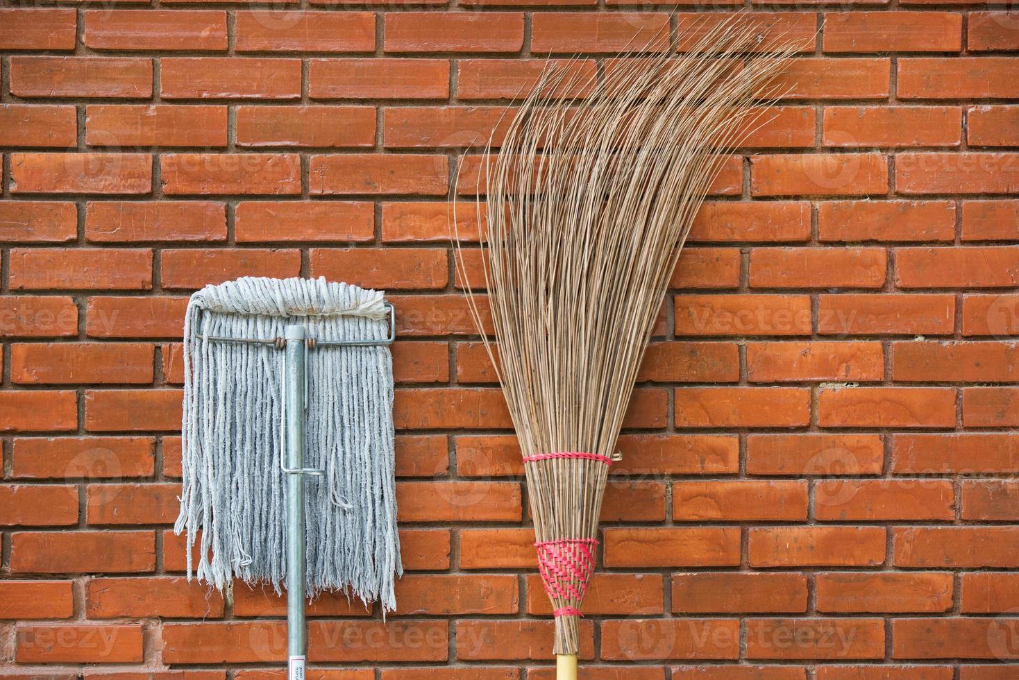 Straw broom with mop against the wall 2 photo