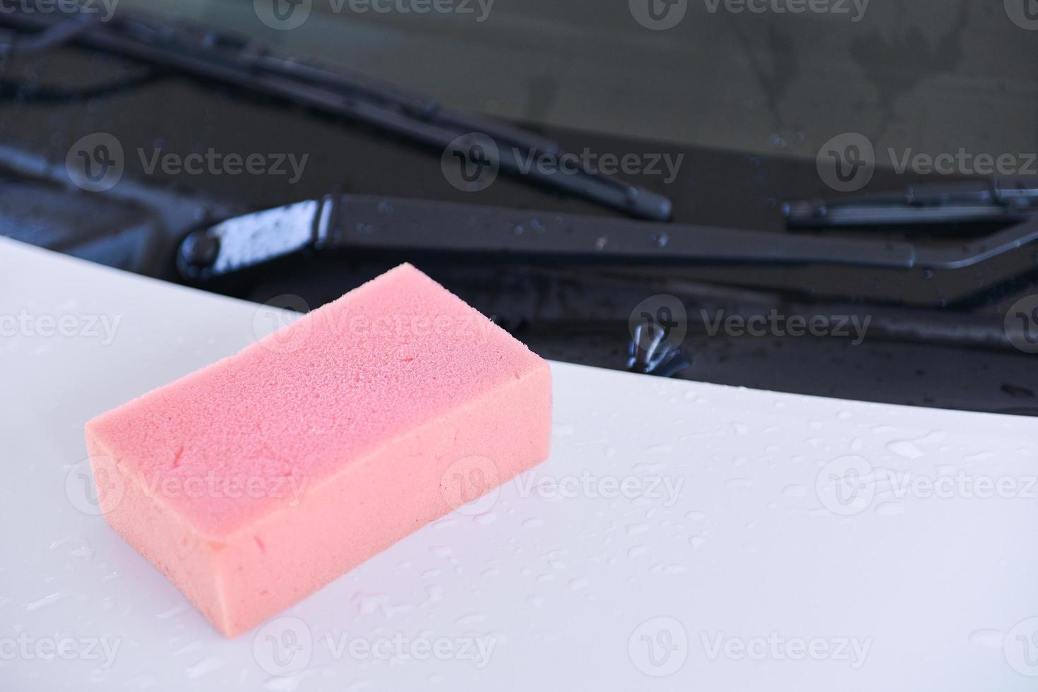 soaking pink sponge on a surface of car photo