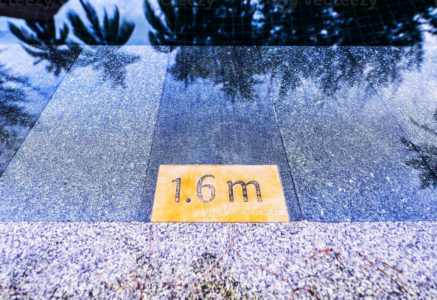 pool depth sign at the edge of the swimming pool photo