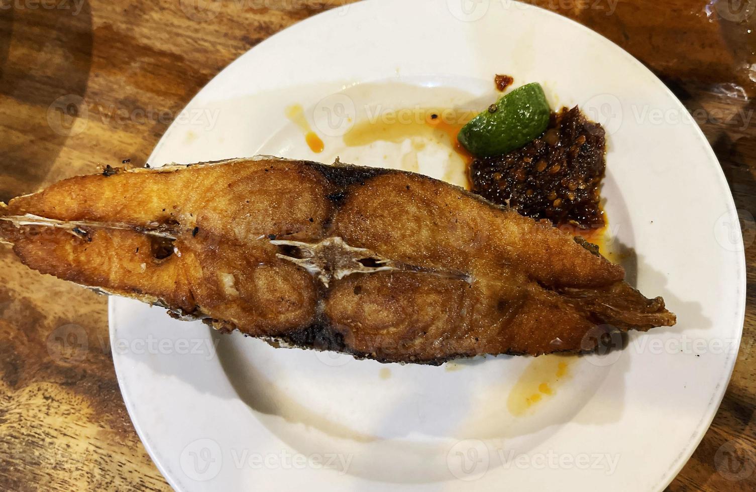 Delicioso pescado caballa española frita con salsa picante y cítricos servido en plato blanco. foto