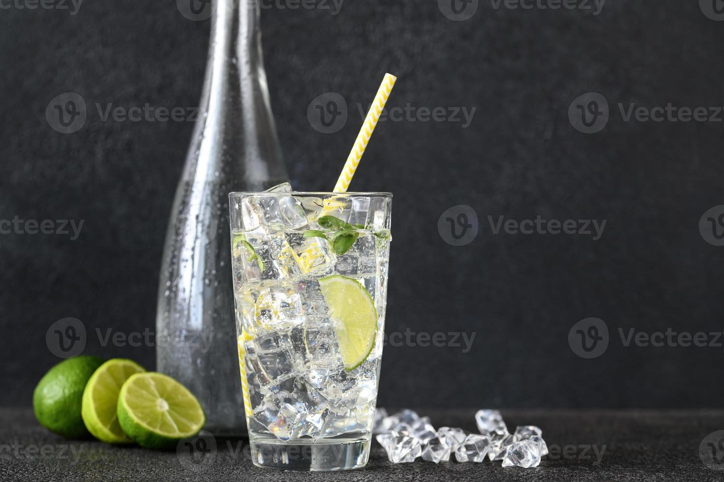 Glass of sparkling water with ice cubes and slice of lime photo