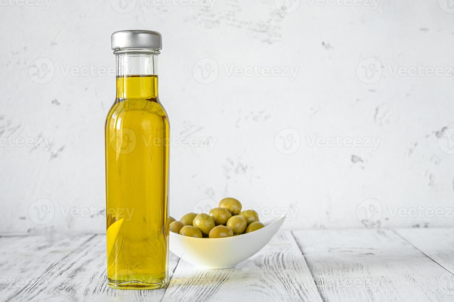 botella de aceite de oliva con aceitunas verdes foto