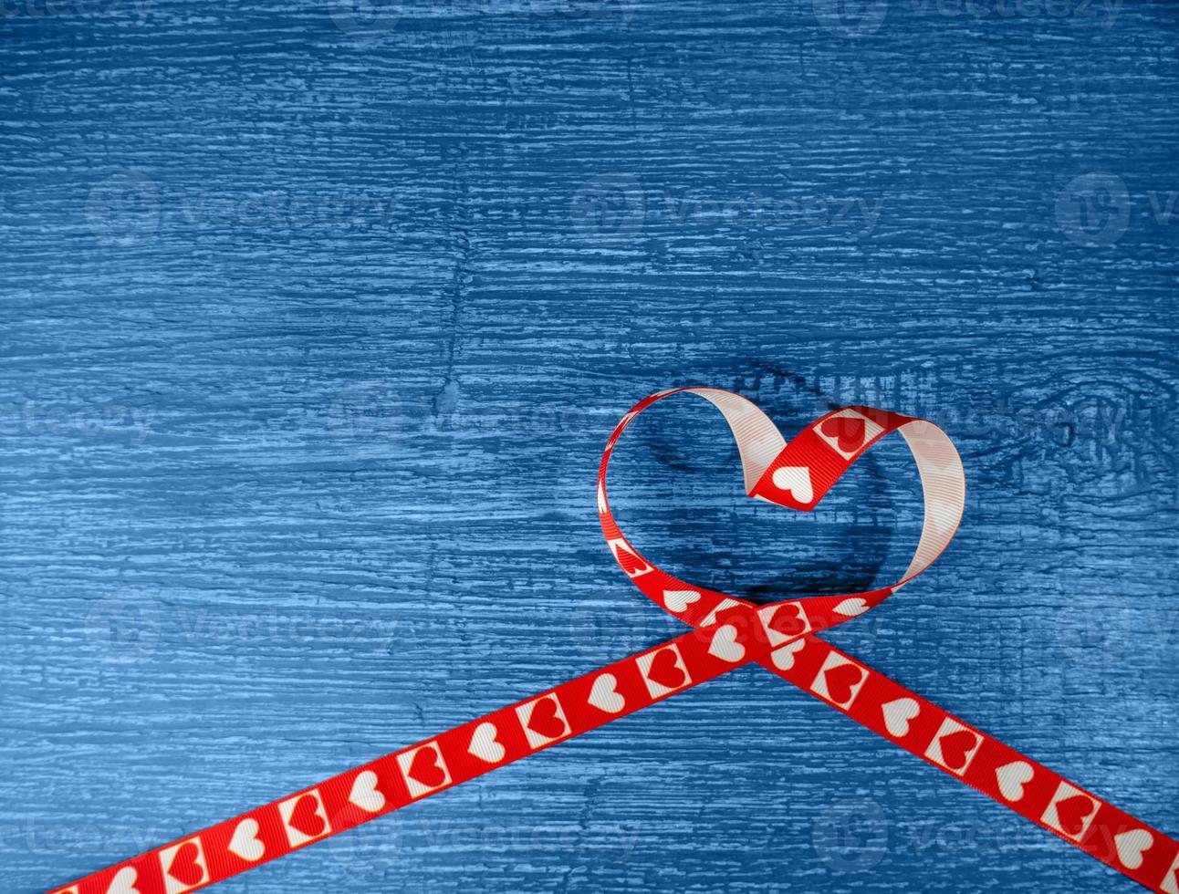 Red heart-shaped ribbon on an old, wooden blue background. Symbol of love photo