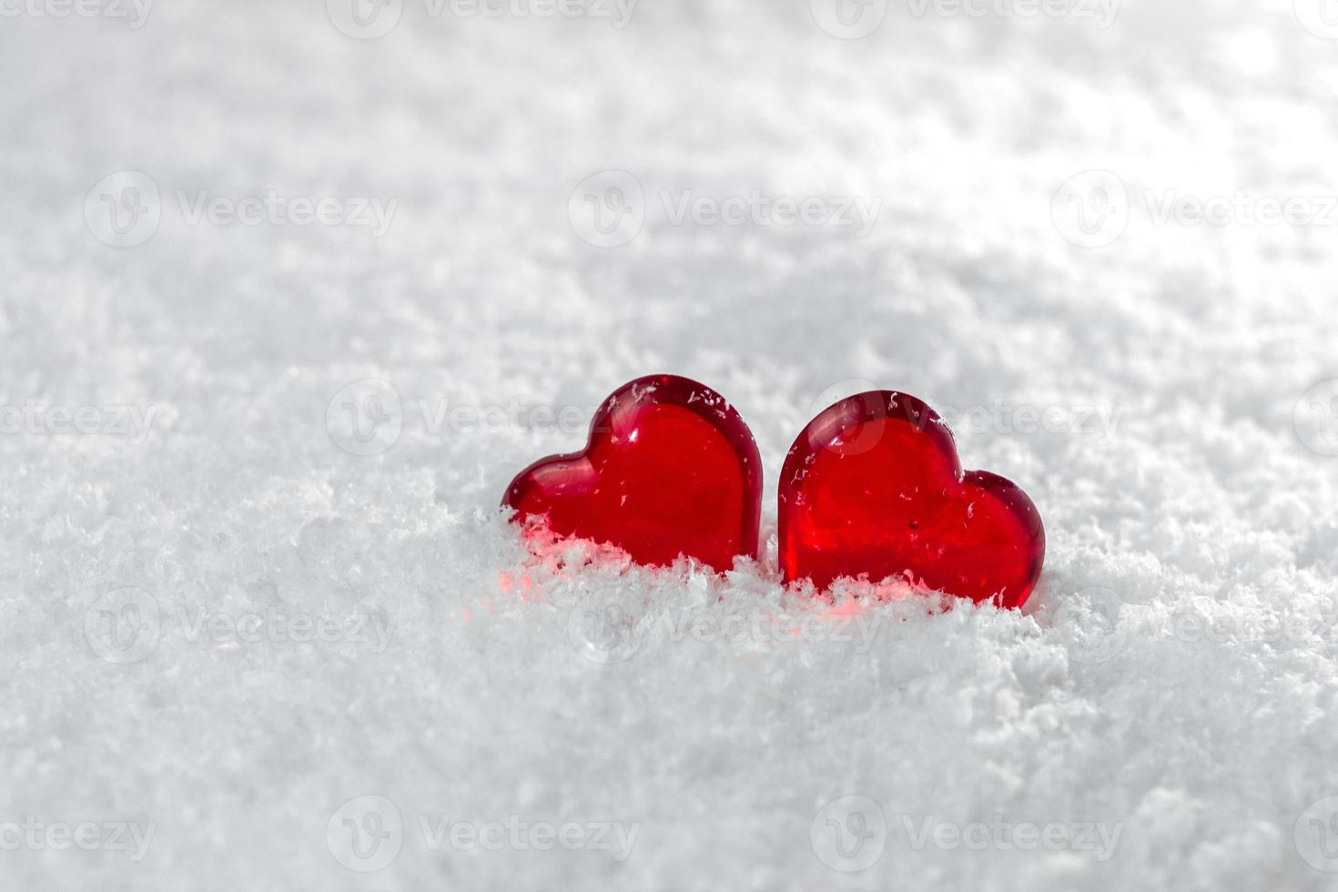 dos corazones rojos yacen en la nieve blanca y esponjosa en invierno símbolo del amor día de san valentín foto