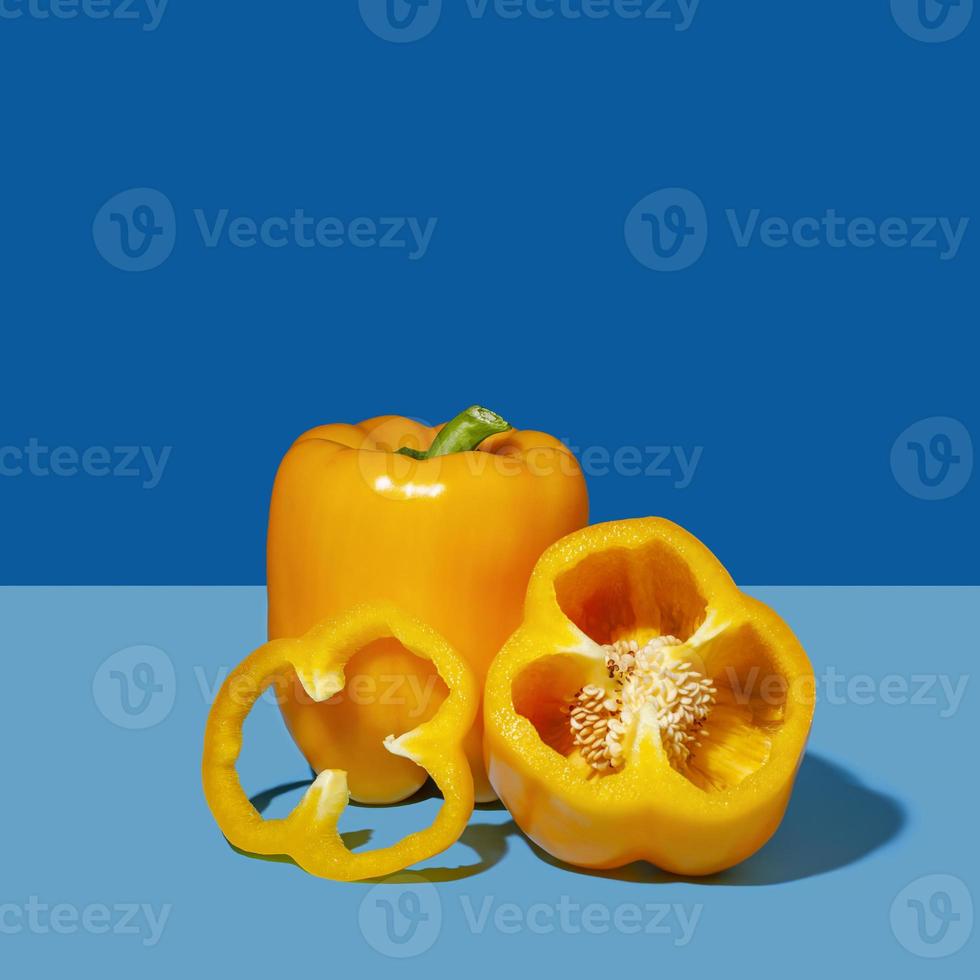 Yellow bell pepper on blue. A bright vegetable in a minimalist style. Pop art design, creative concept of summer food. photo