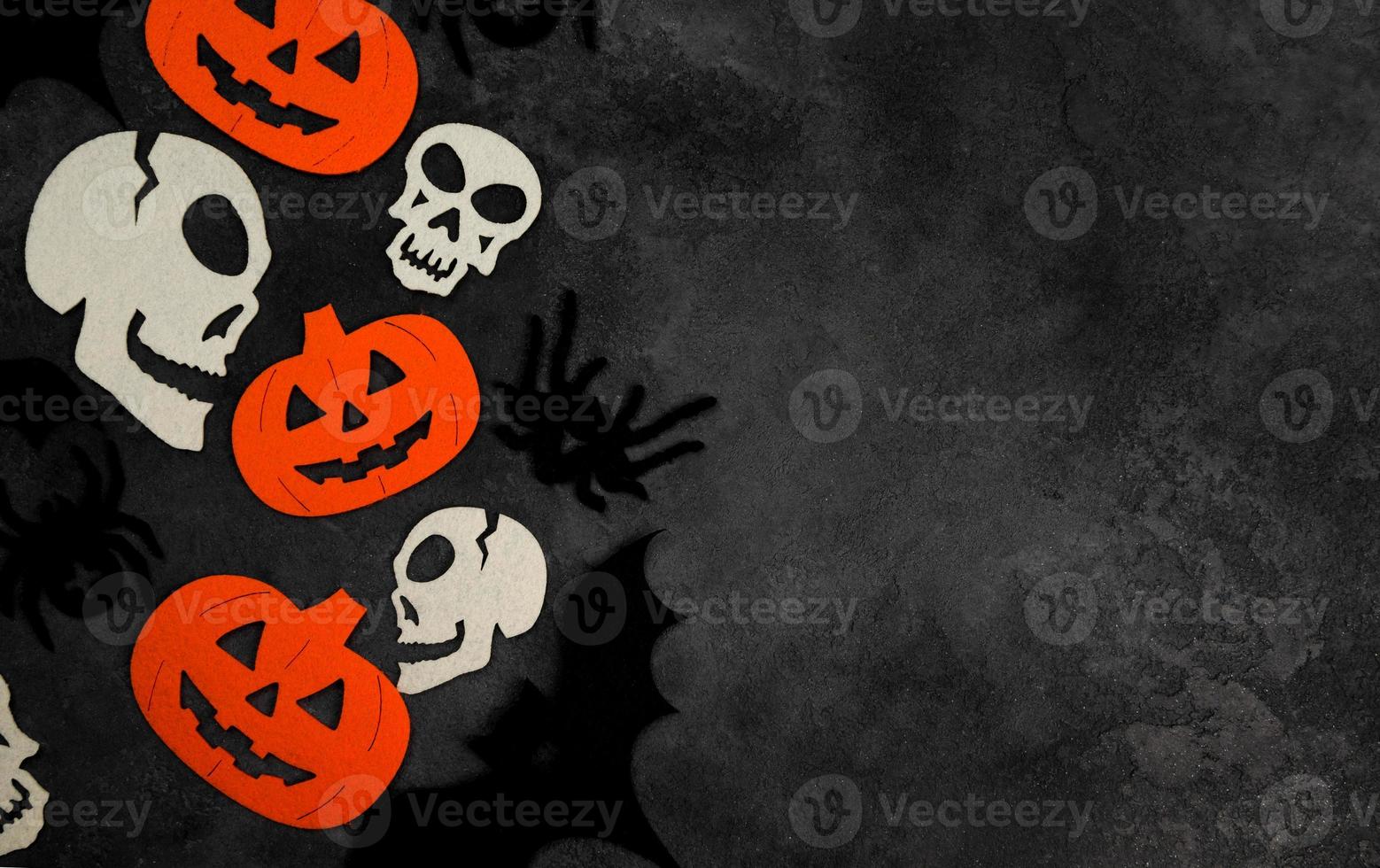 piso de halloween yacía con esqueletos, murciélagos, calabazas y arañas sobre fondo de hormigón negro.banner copyspace foto