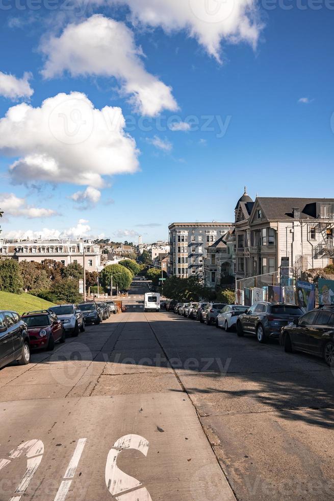 Cars parked on street amidst painted ladies buildings in city photo