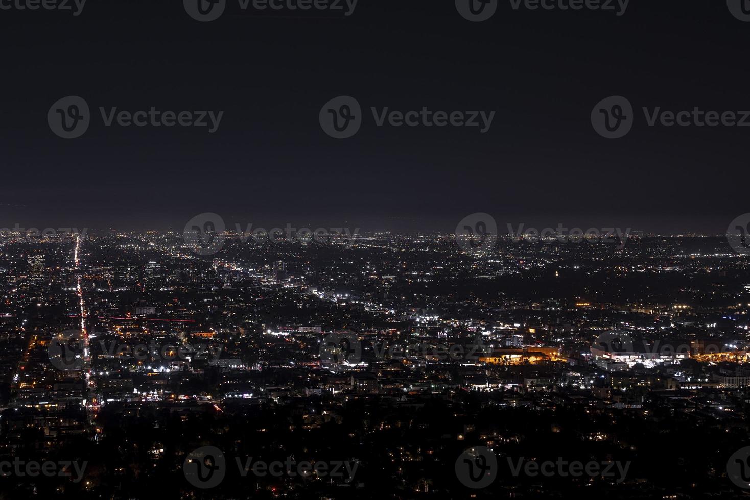 Drone shot of illuminated modern cityscape with dark sky in background at night photo
