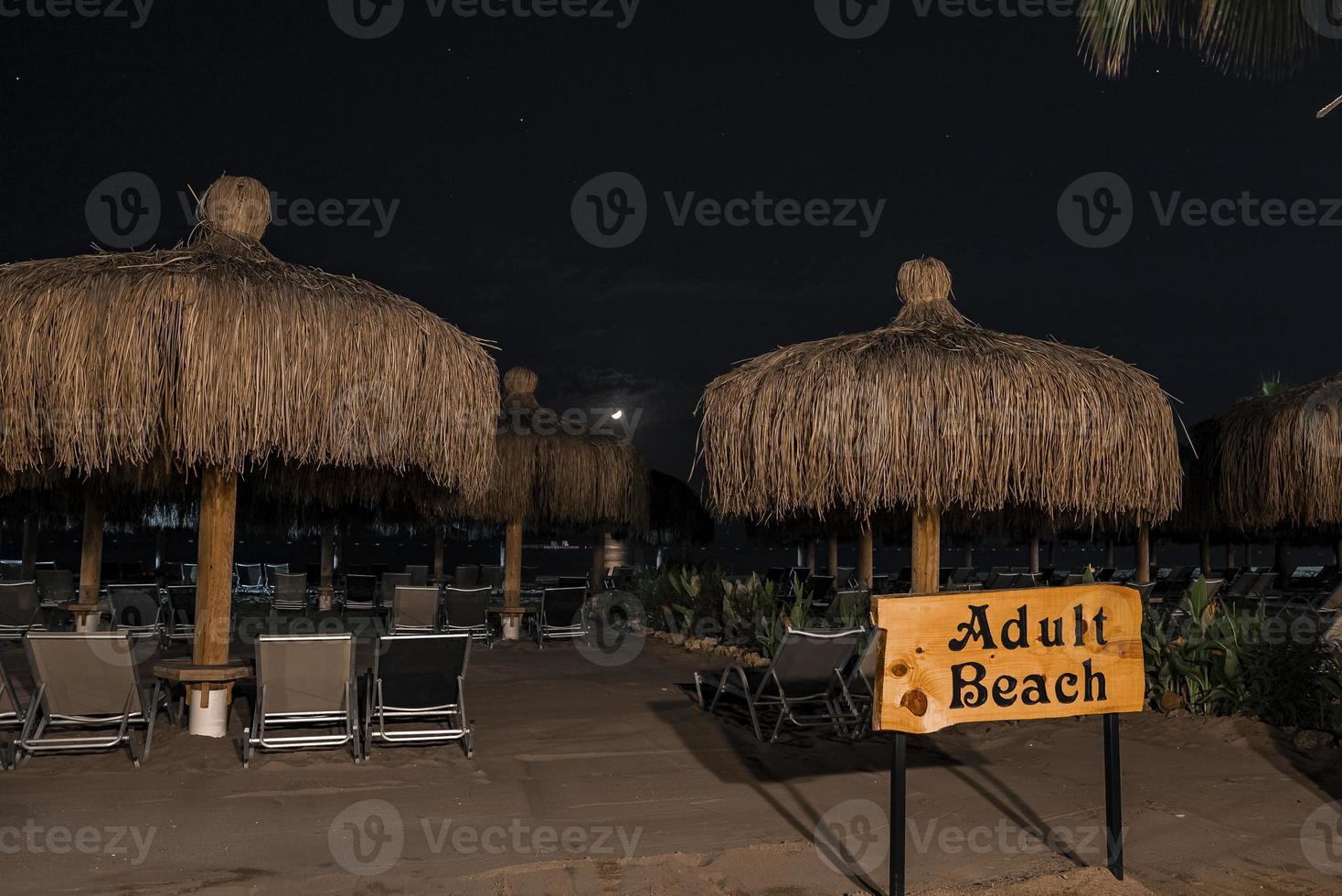 Signboard with deckchairs and parasols arranged at beach photo