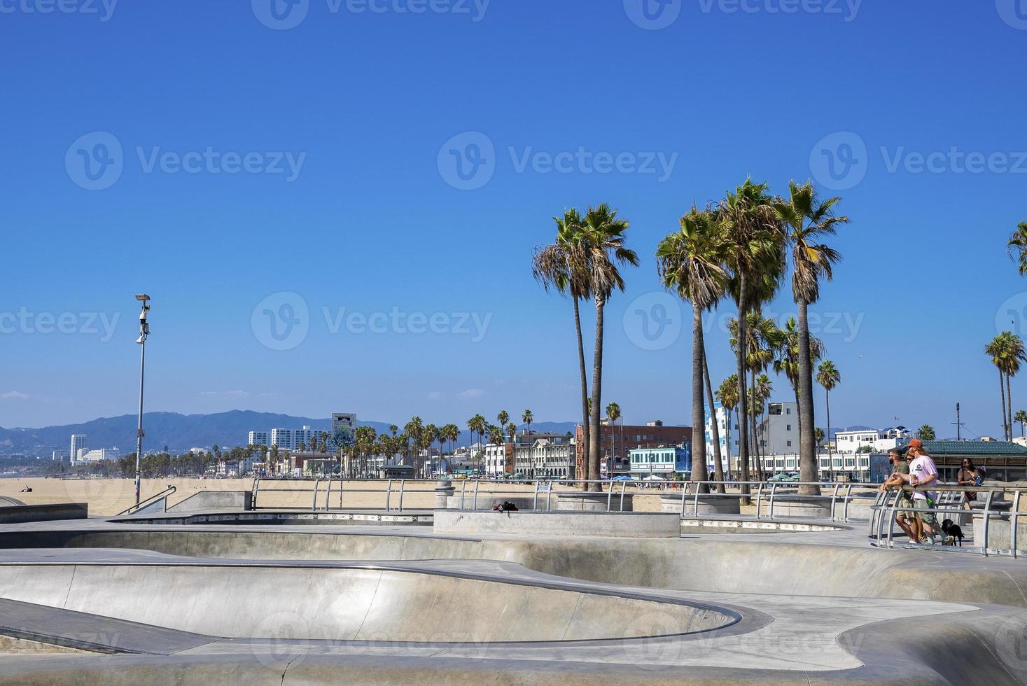 Empty skateboard park and palm trees at Venice beach on sunny day photo