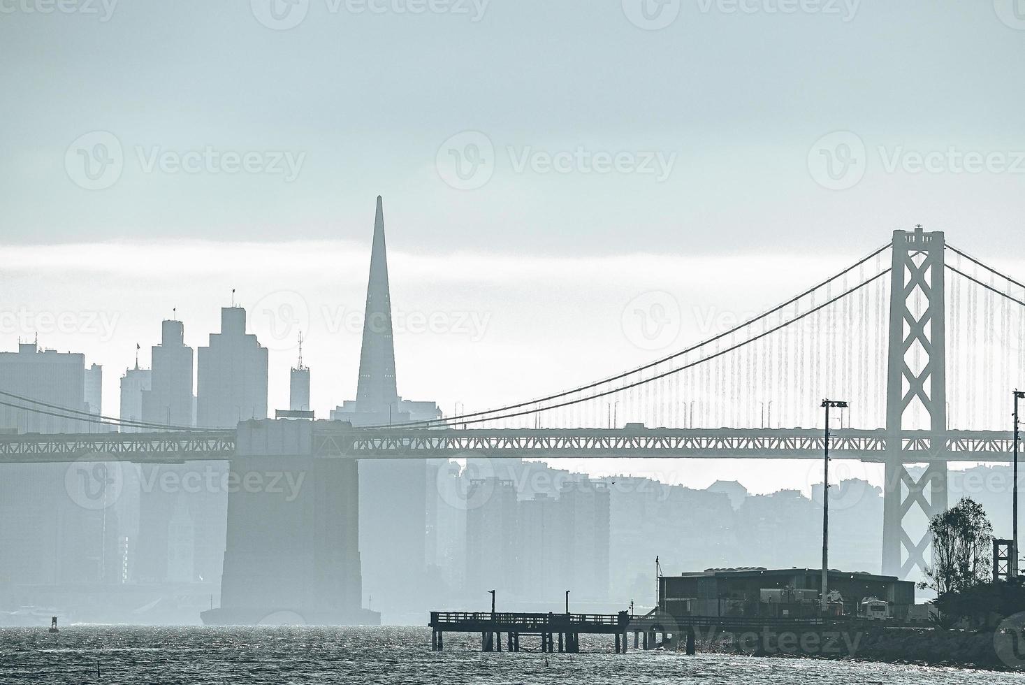 Idyllic view of suspension Bay Bridge and urban skyline with sky in background photo