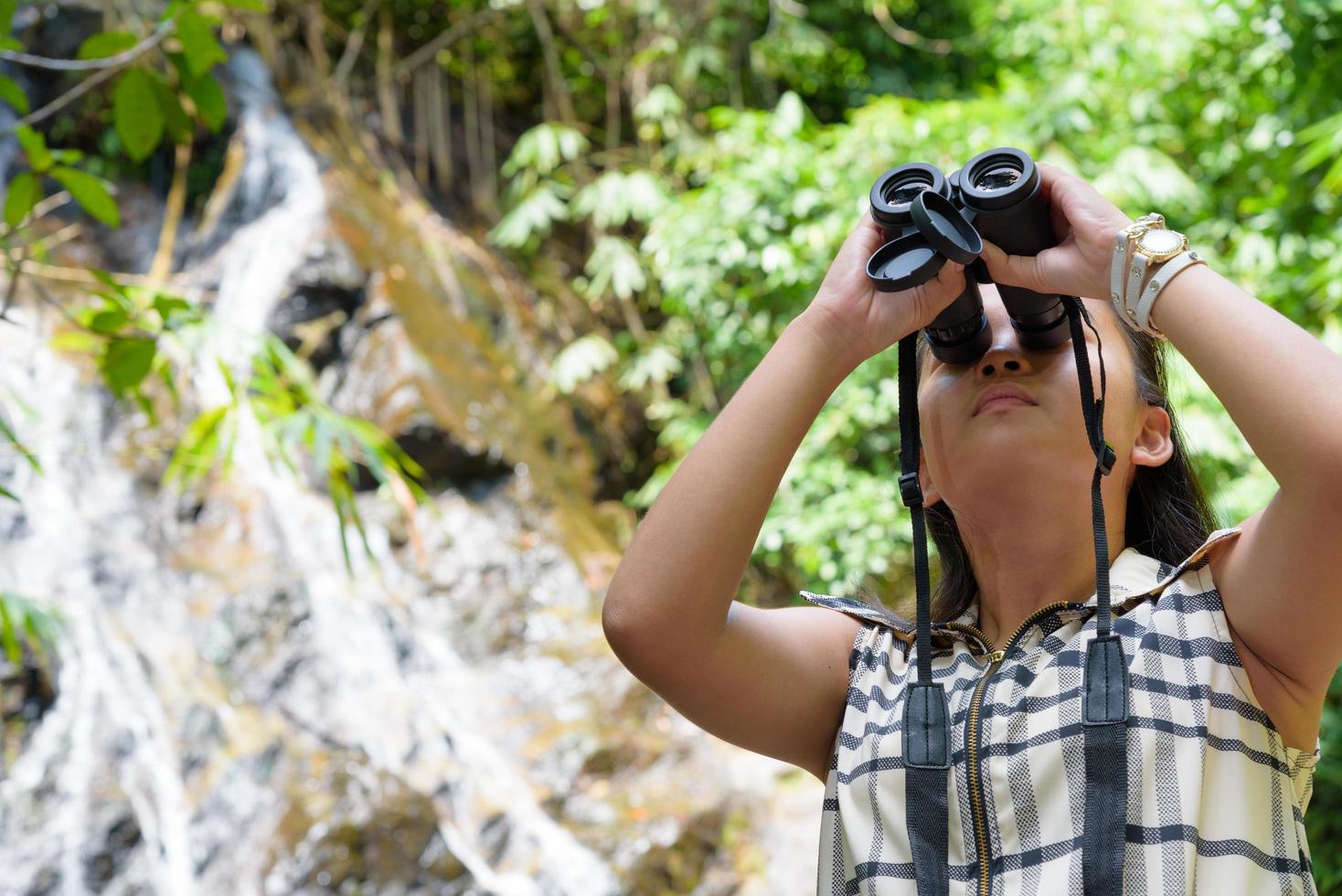 Girl using binoculars in forest photo